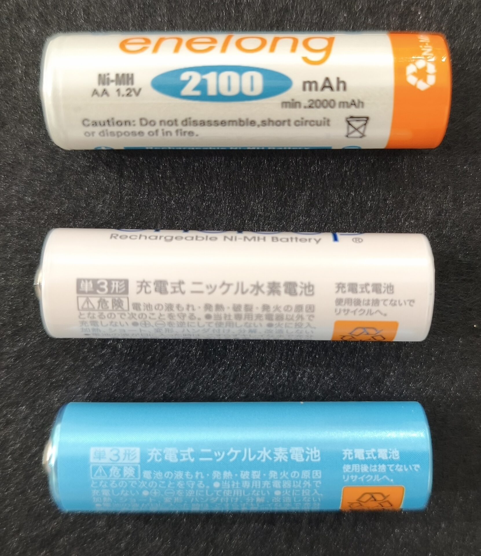 単3形の充電池3本を並べた写真。上段はエネロングの英語表記面（2100mAh・min.2000mAh・Caution表示）、中段と下段はエネループとエネループ ライトの日本語表示面で「単3形 充電式ニッケル水素電池」「危険」「当社専用充電器以外で充電しない」などの注意書きが印字されている