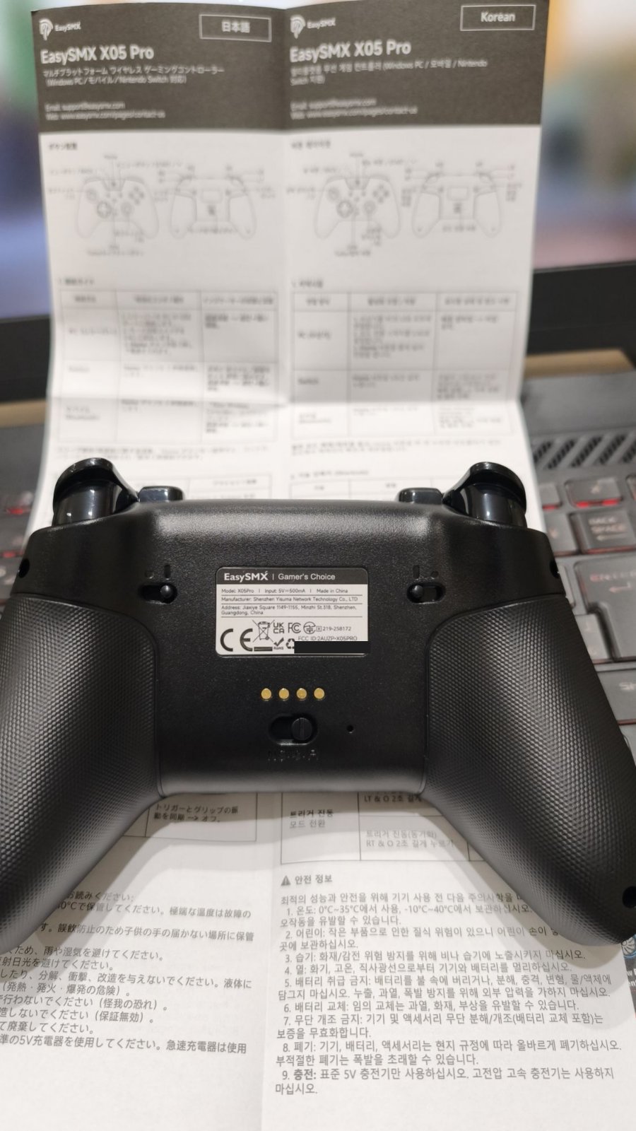 EasySMXコントローラー X05 Proの背面。中央の下側にスライドスイッチ、その上に金色の点4つ、本体ラベル